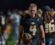Quarterback #4 focuses on his teammate during a night football practice, showcasing teamwork and determination.