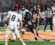 High school football players compete under bright stadium lights, showcasing intense action during a game.