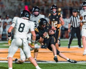 High school football players compete under bright stadium lights, showcasing intense action during a game.