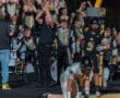 Football fans cheer as a player scores, surrounded by a marching band celebrating in the stands. Excitement fills the air.
