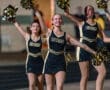 Cheerleaders in glittering uniforms performing at a night game, showcasing team spirit with vibrant pom-poms.
