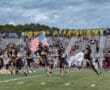 North Allegheny football team running onto the field with flags, energizing the crowd before a game.