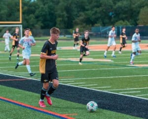 Youth soccer game in action, showing players sprinting on a vibrant turf field with a focus on a player dribbling the ball.