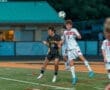 Two soccer players jump for the ball during a night match, showcasing athleticism and teamwork on the field.