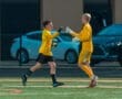 Young soccer goalkeepers celebrating a successful play with a fist bump on the field. Team spirit in action!