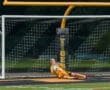 Young goalkeeper in yellow jersey making a save during a soccer game, with a colorful ball in the net.