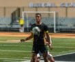 A soccer player in a black and yellow uniform skillfully controls the ball on the field during a match.