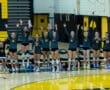 Volleyball team cheers enthusiastically from the bench, showing team spirit and excitement during a match.