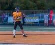 High school football player in yellow jersey, preparing for the game on the field with teammates in the background.