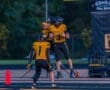 Wexford football players celebrate a touchdown during a night game, showcasing teamwork and school spirit.