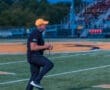 A football coach passionately celebrates on the field during a night game, energizing the crowd and team.