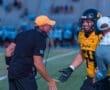 Coach passionately communicates with a player during a football game, showcasing team strategy and excitement on the field.