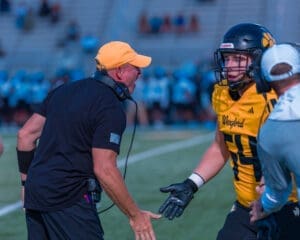 Coach passionately communicates with a player during a football game, showcasing team strategy and excitement on the field.