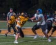 High school football players clash on the field, showcasing intense competition under stadium lights.