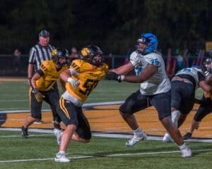 High school football players clash on the field, showcasing intense competition under stadium lights.