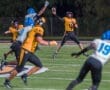 Quarterback wearing number 4 throws a pass while evading defenders during a night football game on the field.