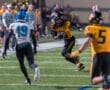 Football player in yellow jersey dodges opponent in blue during night game on the field, showcasing athleticism and competition.