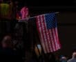 American flag waving in a crowded event, symbolizing patriotism and the spirit of celebration.