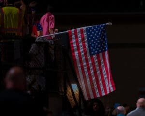 American flag waving in a crowded event, symbolizing patriotism and the spirit of celebration.