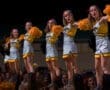 Cheerleaders performing with pom-poms at a night event, showcasing team spirit and excitement in vibrant uniforms.