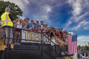 Group of excited fans cheering at a sports event, wearing team colors and U.S. flag attire, celebrating with enthusiasm.