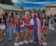 Group of friends dressed in patriotic outfits, smiling together at an outdoor event with a festive atmosphere.