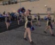 Cheerleaders in black and gold outfits perform with pom-poms at a school event, showcasing team spirit.