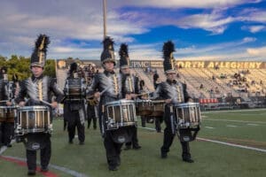 Marching band members in uniforms play drums on the field during a performance at North Allegheny High School.