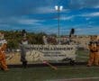 North Allegheny High School marching band presents their banner at a football game, featuring mascots and band members.