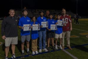 Students receive academic achievement awards during a night sports event, celebrating their success on the field.