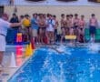Water polo match: coach monitors swimmers as they compete, while teammates cheer from the sidelines.