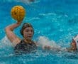 Water polo action shot: a player prepares to throw a water polo ball while another player defends nearby.