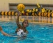 Water polo player in action, preparing to throw the ball while another player attempts to defend in the pool.