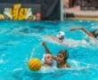 Two female water polo players compete for the ball in a vibrant blue pool, showcasing athleticism and teamwork.