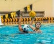 Water polo players compete in the pool, one preparing to throw the ball while the other defends.