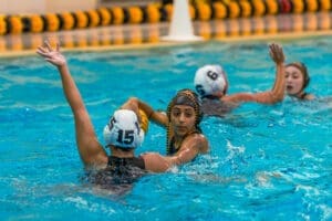 High school water polo players compete in the pool, showcasing teamwork and athleticism during a match.