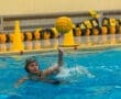 Young female water polo player prepares to pass a ball in a swimming pool, showcasing sports skills and determination.