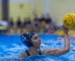 A water polo player in action, poised to throw the ball during a competitive match in an aquatic setting.