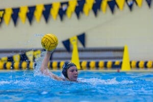 Water polo athlete prepares to throw a yellow water polo ball, showcasing skill and determination in the pool.