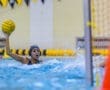 Girl throwing a water polo ball during a competitive game in a pool, showcasing athletic skill and teamwork.