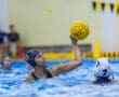 Young female water polo player making a powerful pass during a match, showcasing skill and determination in the pool.