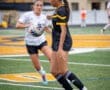 Two female soccer players compete for the ball on a field, showcasing athleticism during a match.