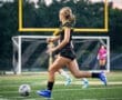 A soccer player sprinting on the field, showcasing athleticism and determination during a match at dusk.