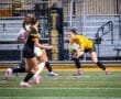 Goalkeeper in yellow makes a save during a soccer match, with players in action on the field.