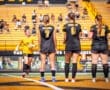 Goalkeeper runs onto the field as her teammates prepare for a soccer match, showcasing team spirit and strategy.
