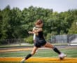 Young female soccer player kicking a soccer ball on a field during a game, showcasing athleticism and energy.