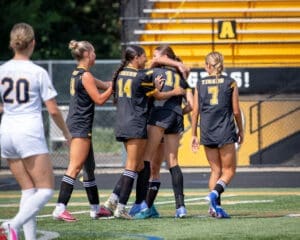 Cheering girls’ soccer team celebrates a goal on the field, highlighting teamwork and sportsmanship in action.