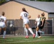 Female soccer players in action, with a focus on a player kicking the ball during a match on a sunny day.