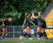 Female soccer players celebrating a goal on the field, showcasing teamwork and sportsmanship during the game.