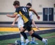 Two soccer players compete for possession of the ball on a vibrant field during an intense match moment.
